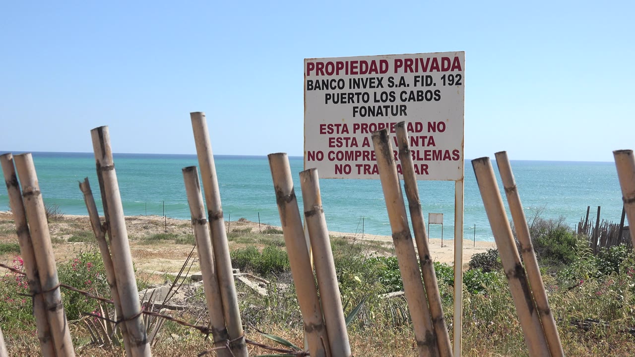 Private property sign behind wooden fence posts near a beach