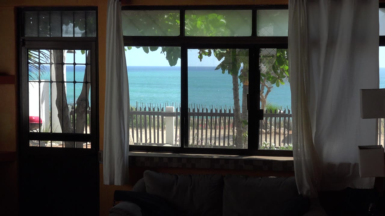 At 0:00, a shaded room in the Grand Junction Colorado 2017 clip frames a bright ocean view through a door and window, with white curtains, a fence, and no visible people.
