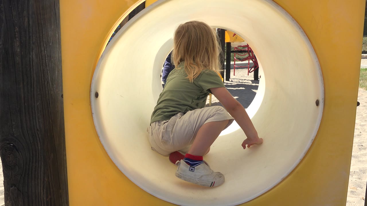 Child sitting inside a round playground tunnel.