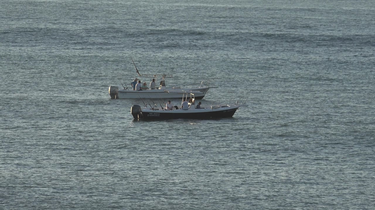 Pair of grey boats crossing rippled water.