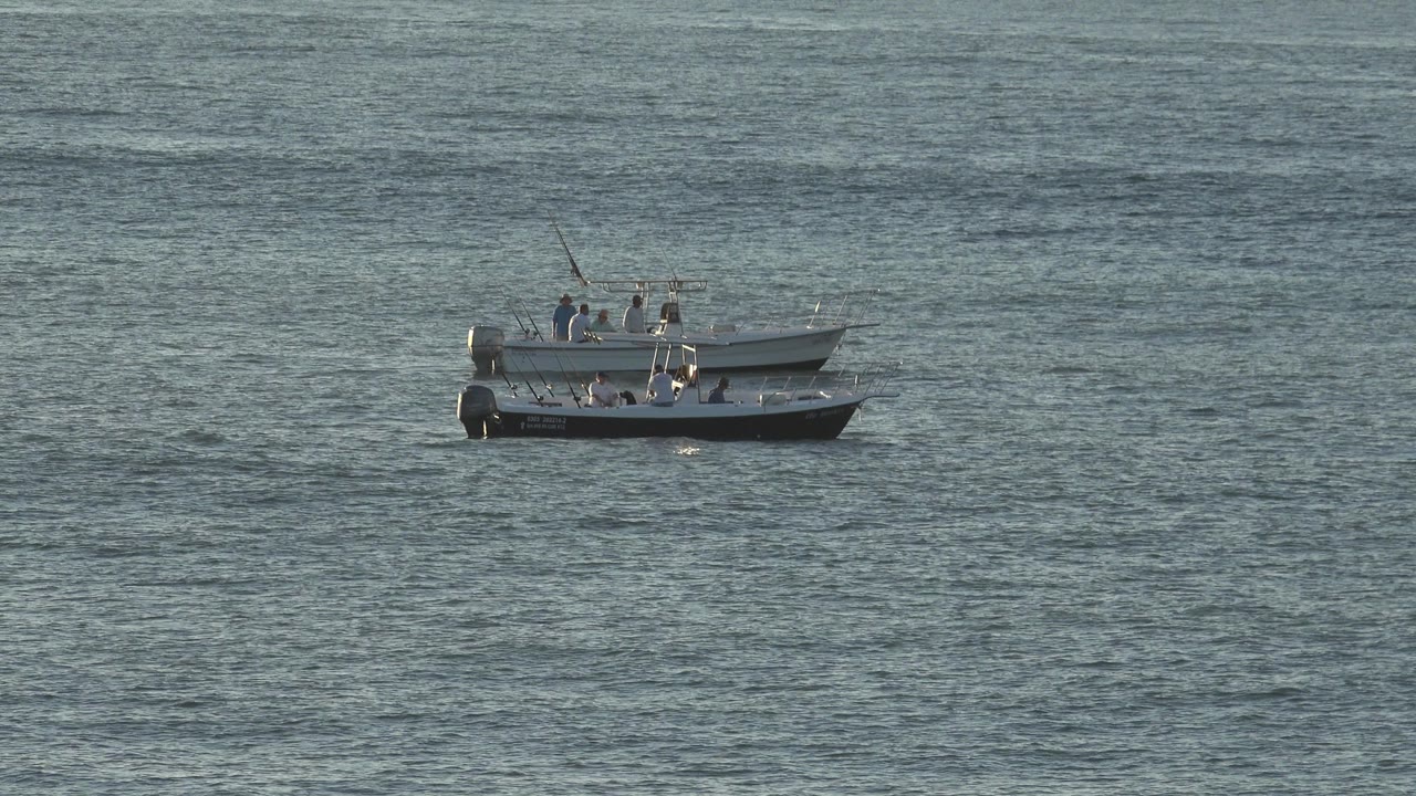 Two small motorboats with people aboard sit far out on rippled water in the Grand Junction, Colorado 2017 footage, with the boats grouped near the upper left of the frame.