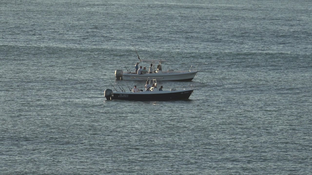 Two small boats with people aboard sit side by side on a wide stretch of water in Grand Junction, Colorado, at the start of the clip.