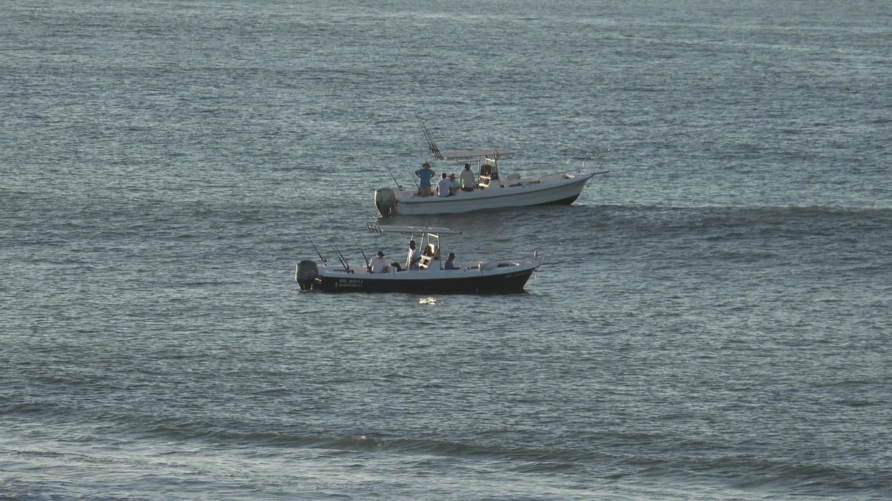 Two small motorboats with people aboard sit on blue-gray rippled water in Grand Junction, Colorado, at the opening moment of the clip.