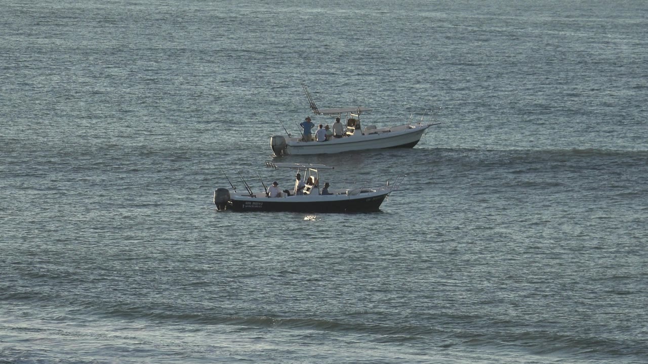 The two boats remain distant on the textured water, with the darker hull lower in frame and the lighter boat higher in Grand Junction, Colorado.