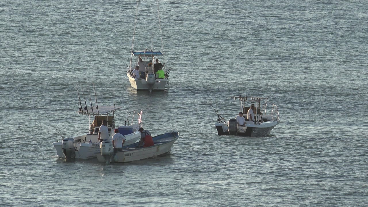 Small fishing boats floating on rippled lake water.