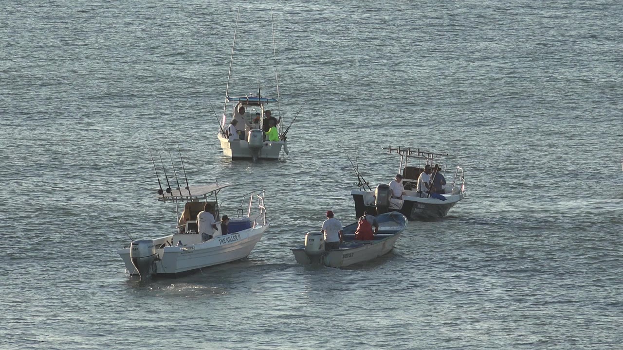 Three small fishing boats with people on open water.