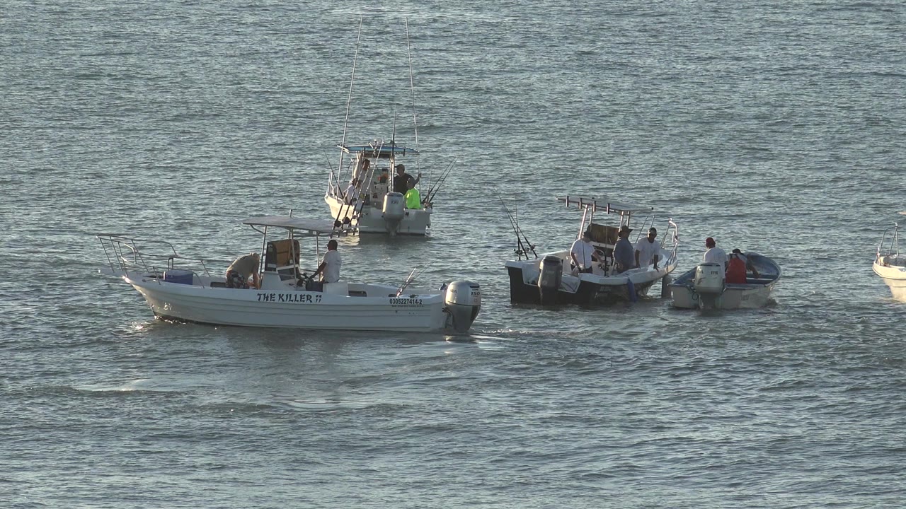 Small motorboats with people on rippled open water.