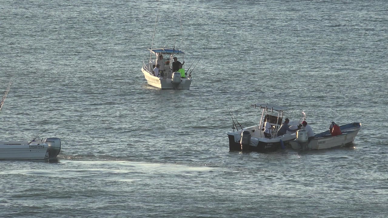 Two small boats on rippled water in bright light.