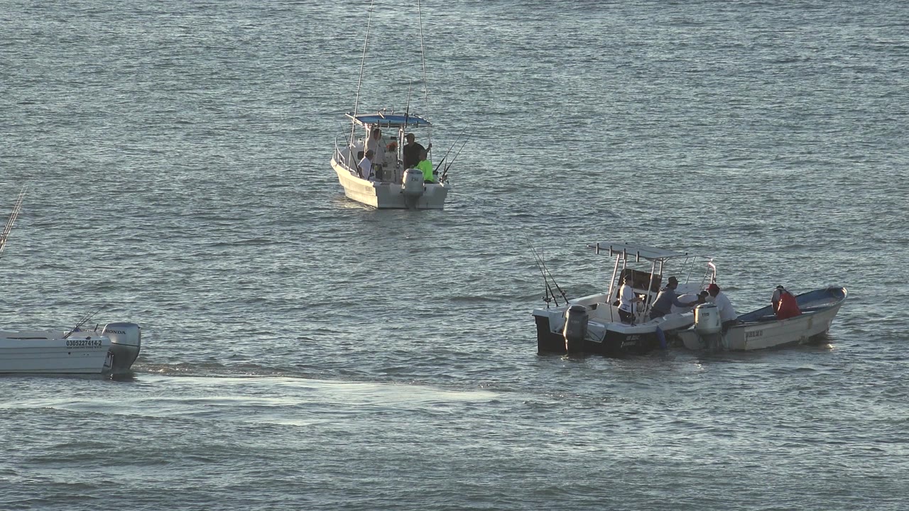 Two motorboats remain in view on blue-gray water in Grand Junction, Colorado, with one boat closer in the lower frame and another farther back near the upper left.