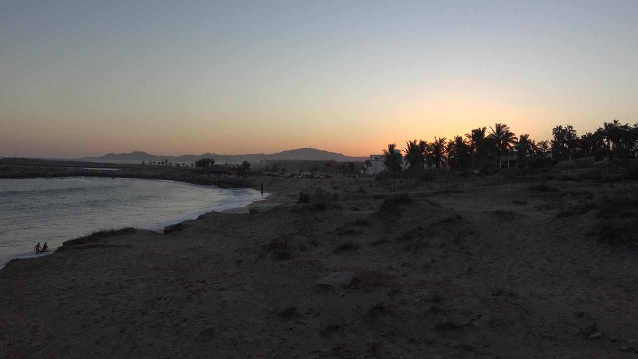 Lake, desert shore, and tree silhouettes at sunset