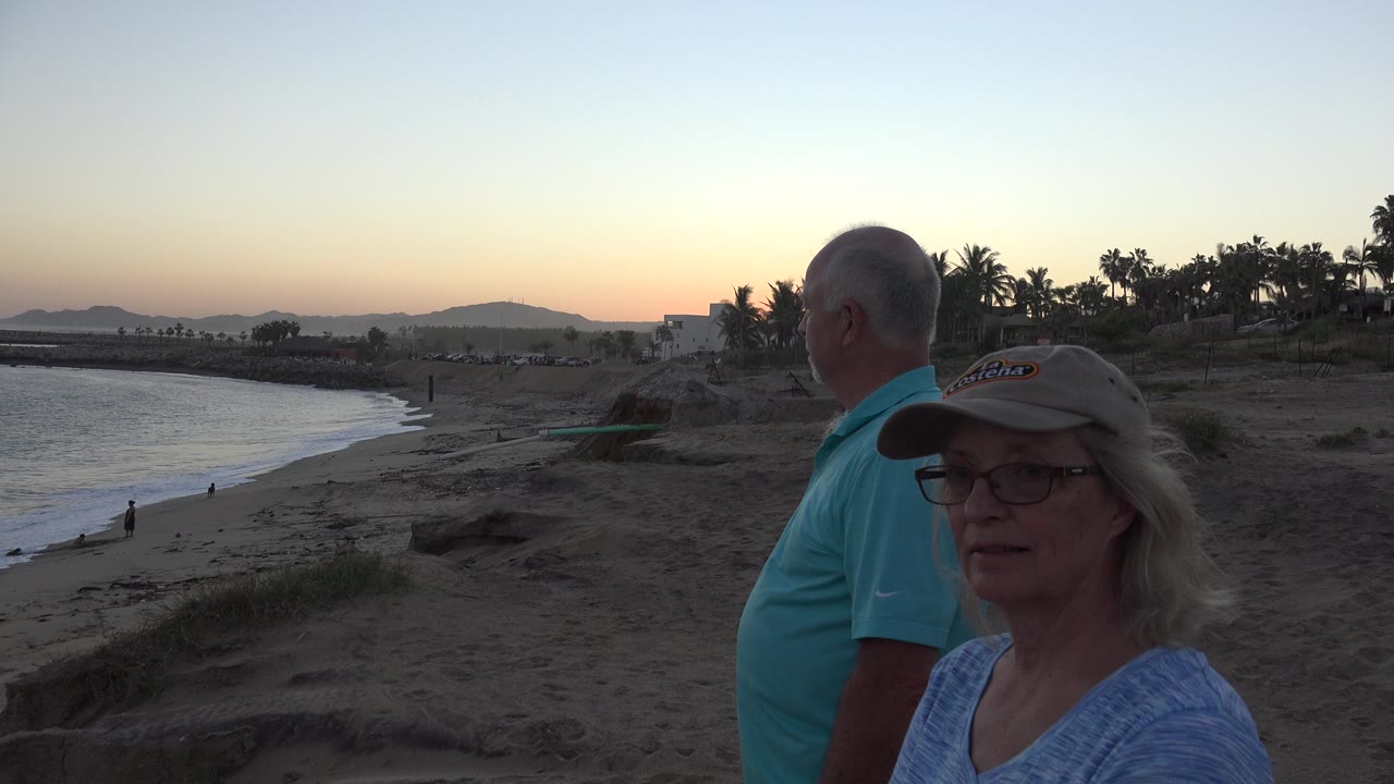 Two adults near a sandy shoreline at sunset