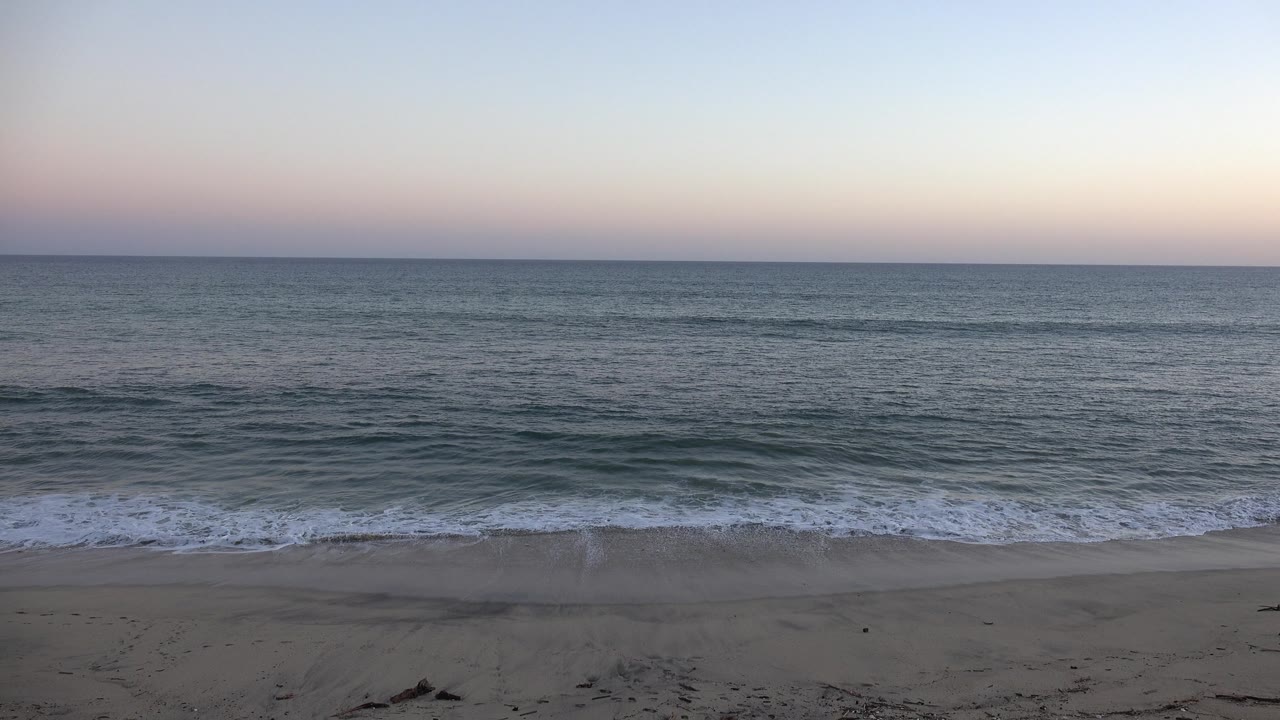 Small shore break beneath a pink and blue horizon