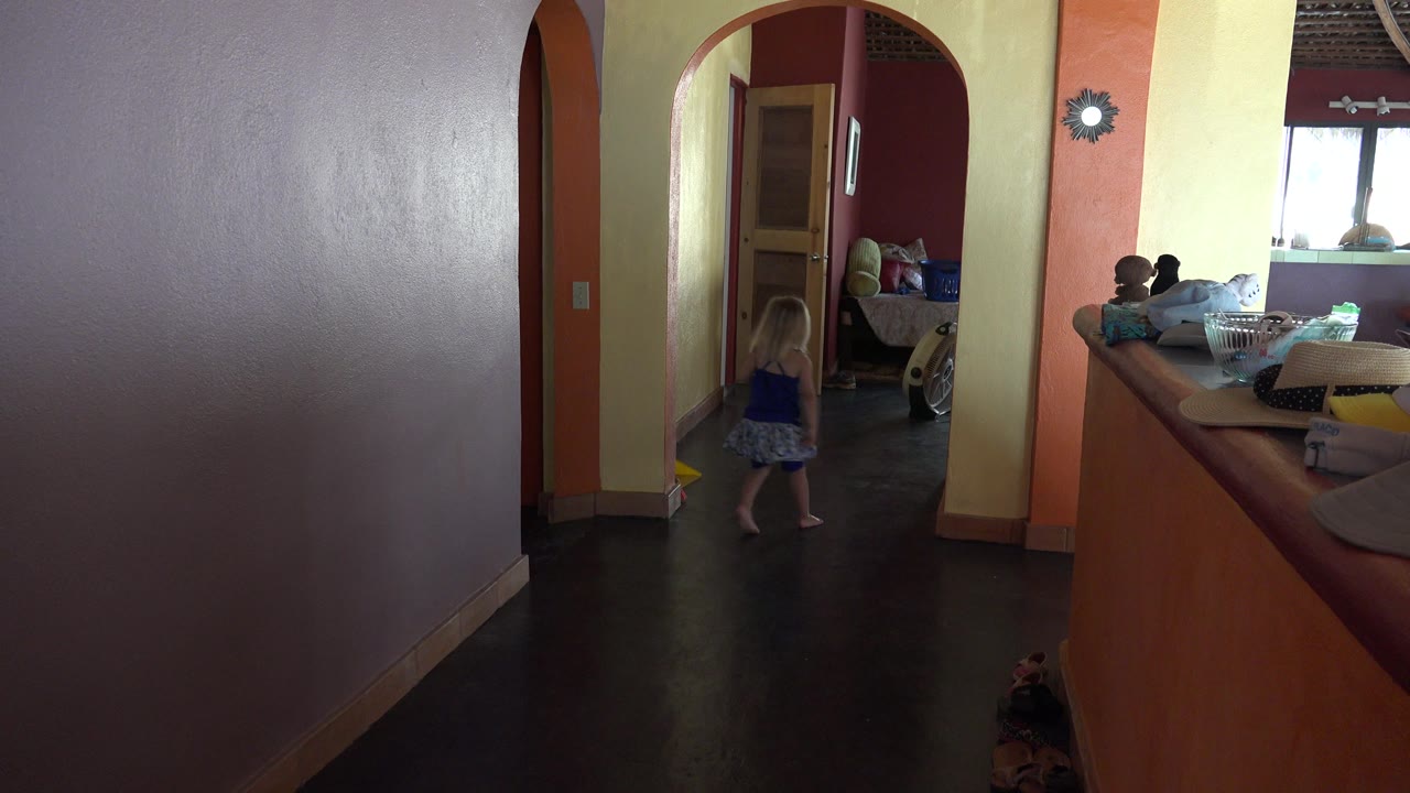Barefoot girl entering an arched doorway inside a colorful home.