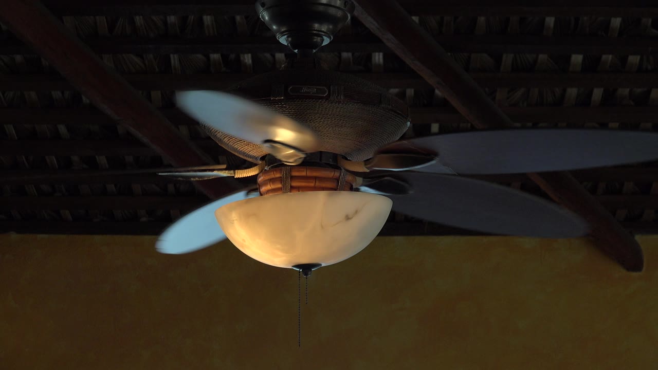 The white fan blades have rotated around the glowing lamp in a tight upward Grand Junction, Colorado interior view with no visible people.