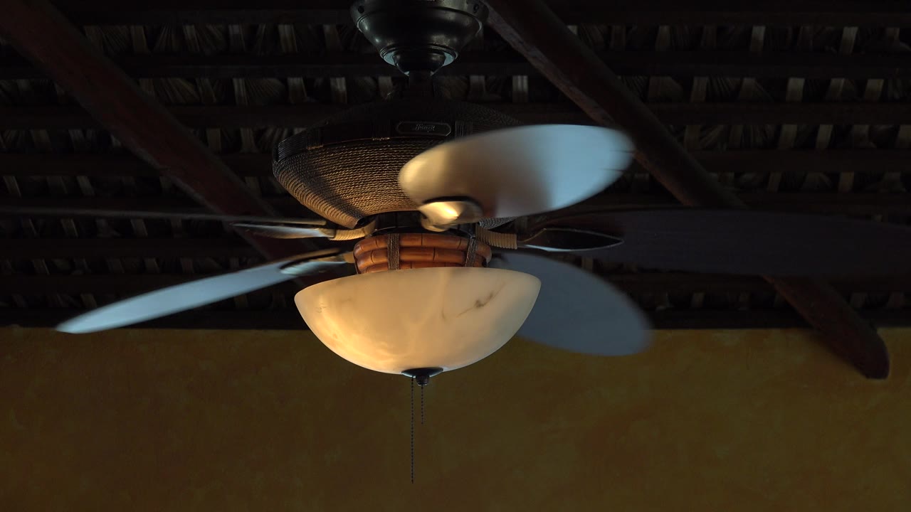 At 0:01, the ceiling fan blades shift position around the warm light fixture beneath a dark beamed ceiling in Grand Junction, Colorado, with no visible people.