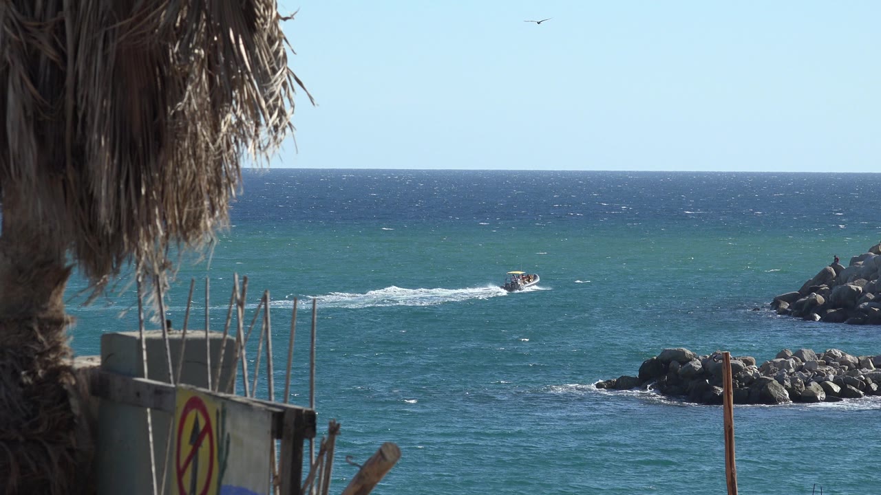 Small motorboat on blue ocean beside rocky shoreline