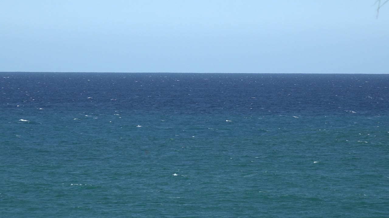 Blue ocean horizon under pale sky