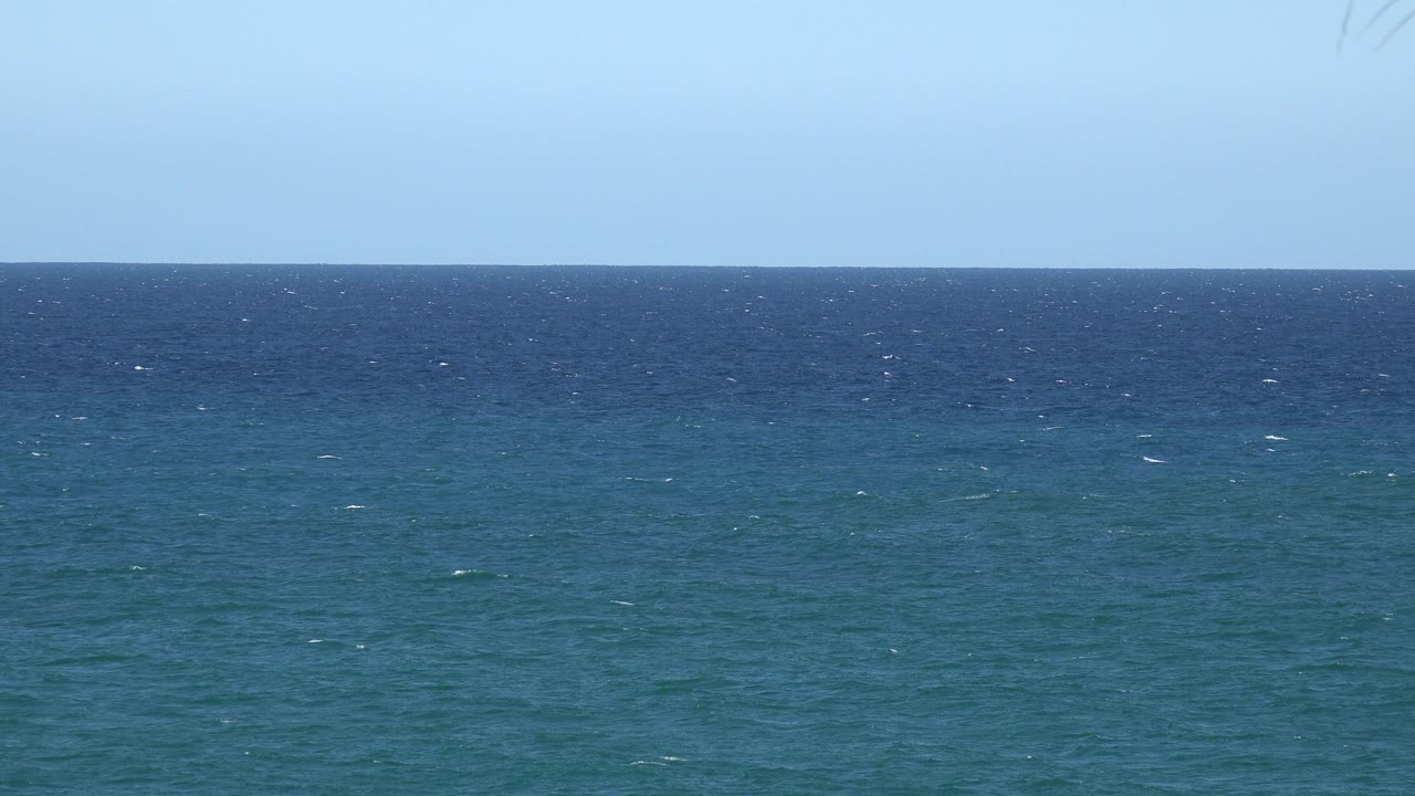 Second frame from the Grand Junction, Colorado catalog clip with the sea surface slightly shifted by wave texture, pale sky above, and no visible people.