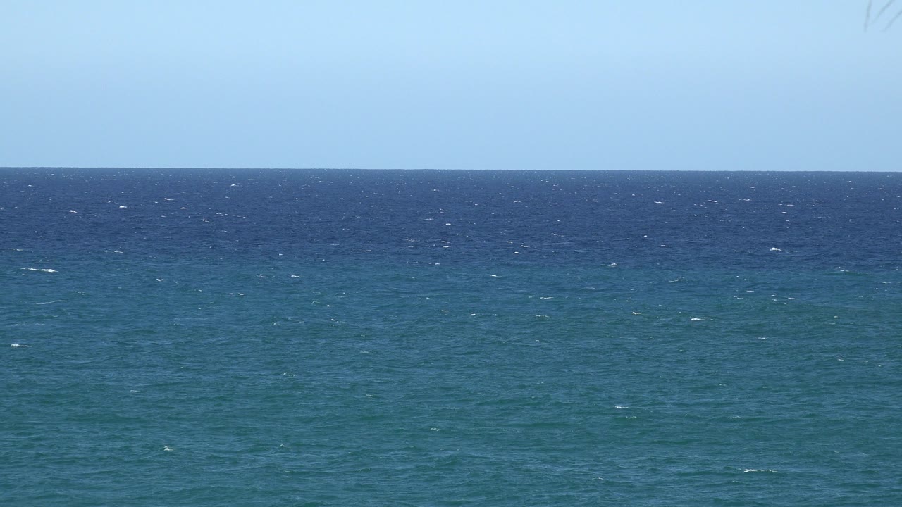 Second frame showing the same open water horizon, with small whitecaps scattered across the blue-green surface and no visible people.