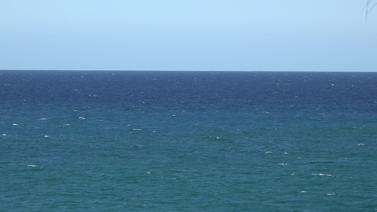 Blue-green ocean water beneath a clear blue sky.