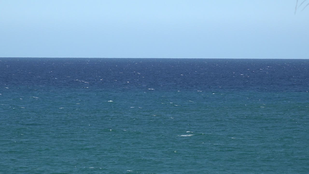 Blue ocean horizon under pale blue sky