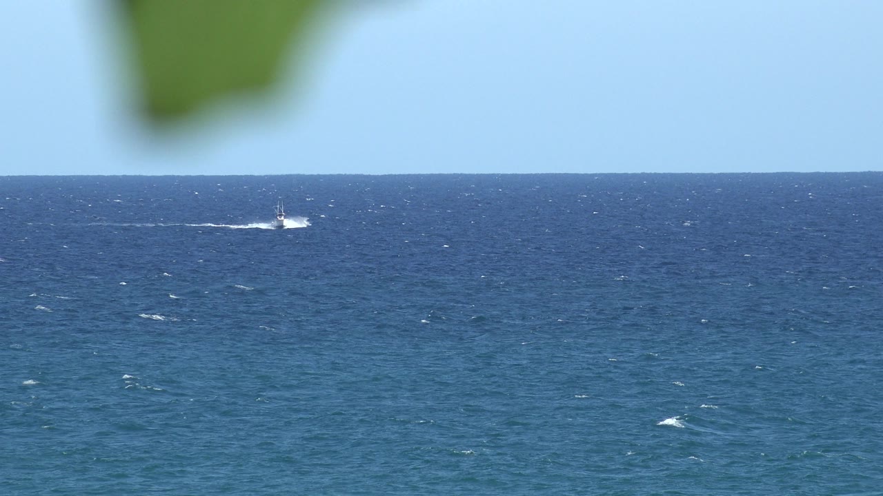 Blue ocean horizon with a distant white boat