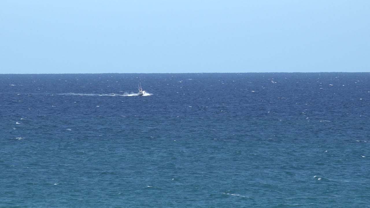 White boat near the far horizon with open water below.