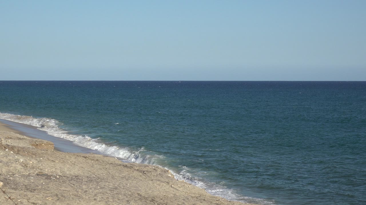 Grand Junction 2017 shoreline view one second in, showing more white surf along the pale sand and a level water horizon with no visible people.