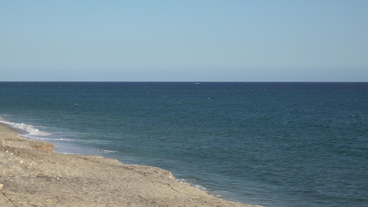 Open blue water and tan shoreline with light surf