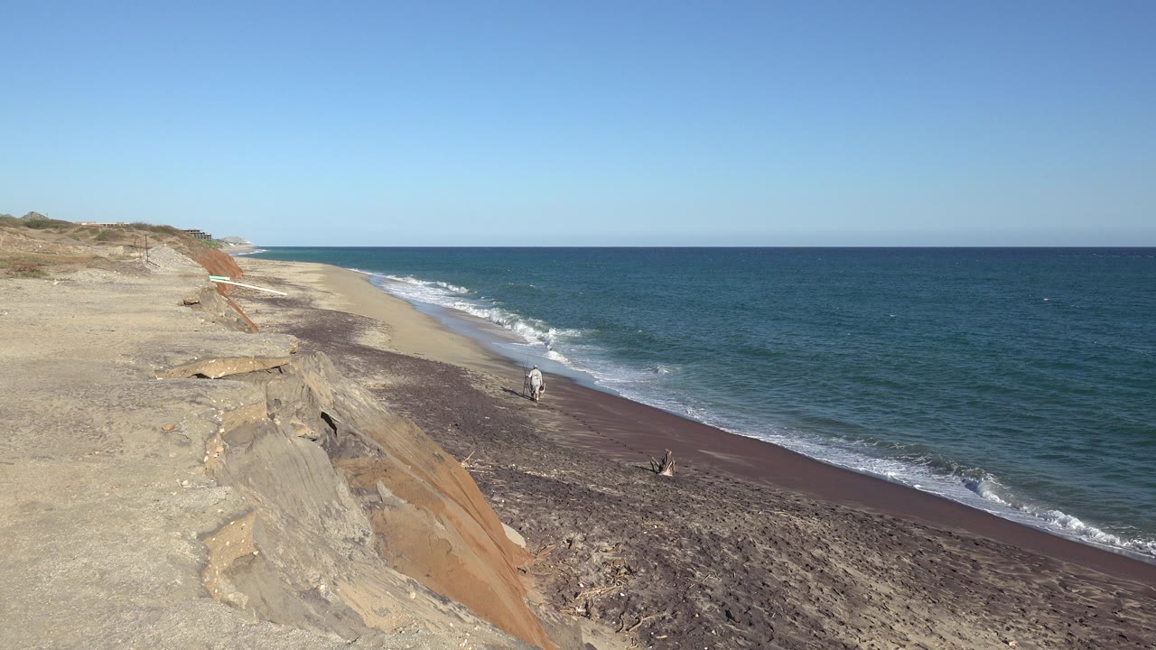 Wide view from a sandy bluff toward a narrow beach and blue water in the Grand Junction, Colorado 2017 clip, with no clearly identifiable people visible.