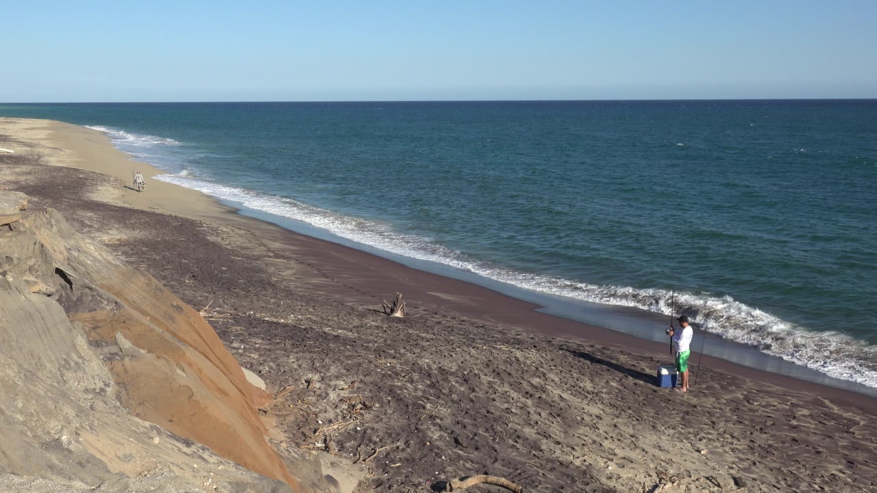The person remains near the lower right edge of the beach while a thin line of white surf advances along the Grand Junction, Colorado shoreline.
