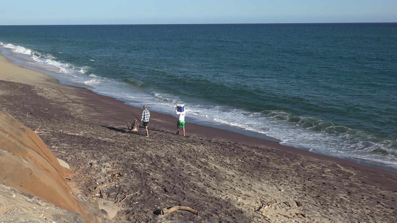 At 0:01, the two people remain near the shoreline in Grand Junction, Colorado, with a fresh line of foam reaching the darker wet sand behind them.