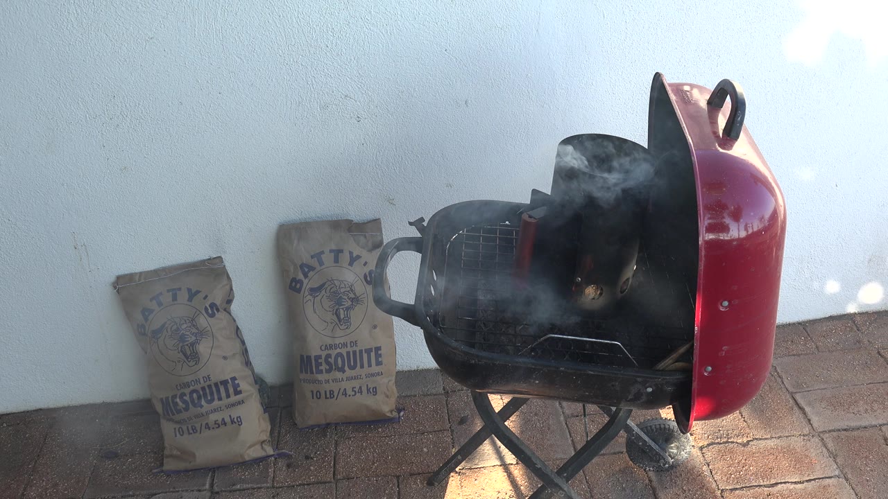 Smoke thickens above a red backyard grill.