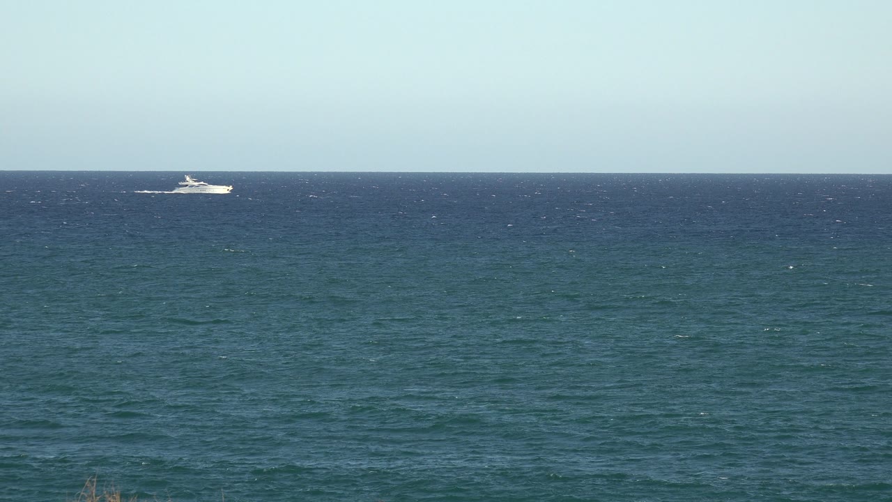 White boat near center-right on a flat water horizon.