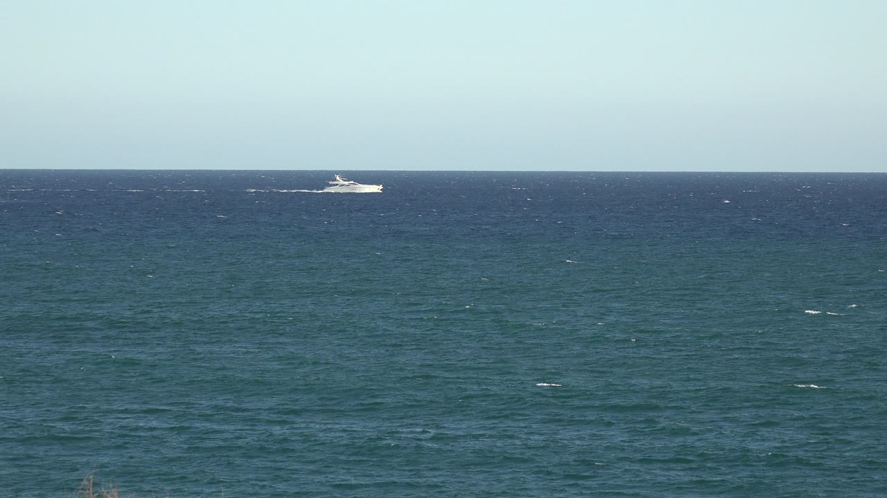 Blue ocean with a distant white boat near the horizon.