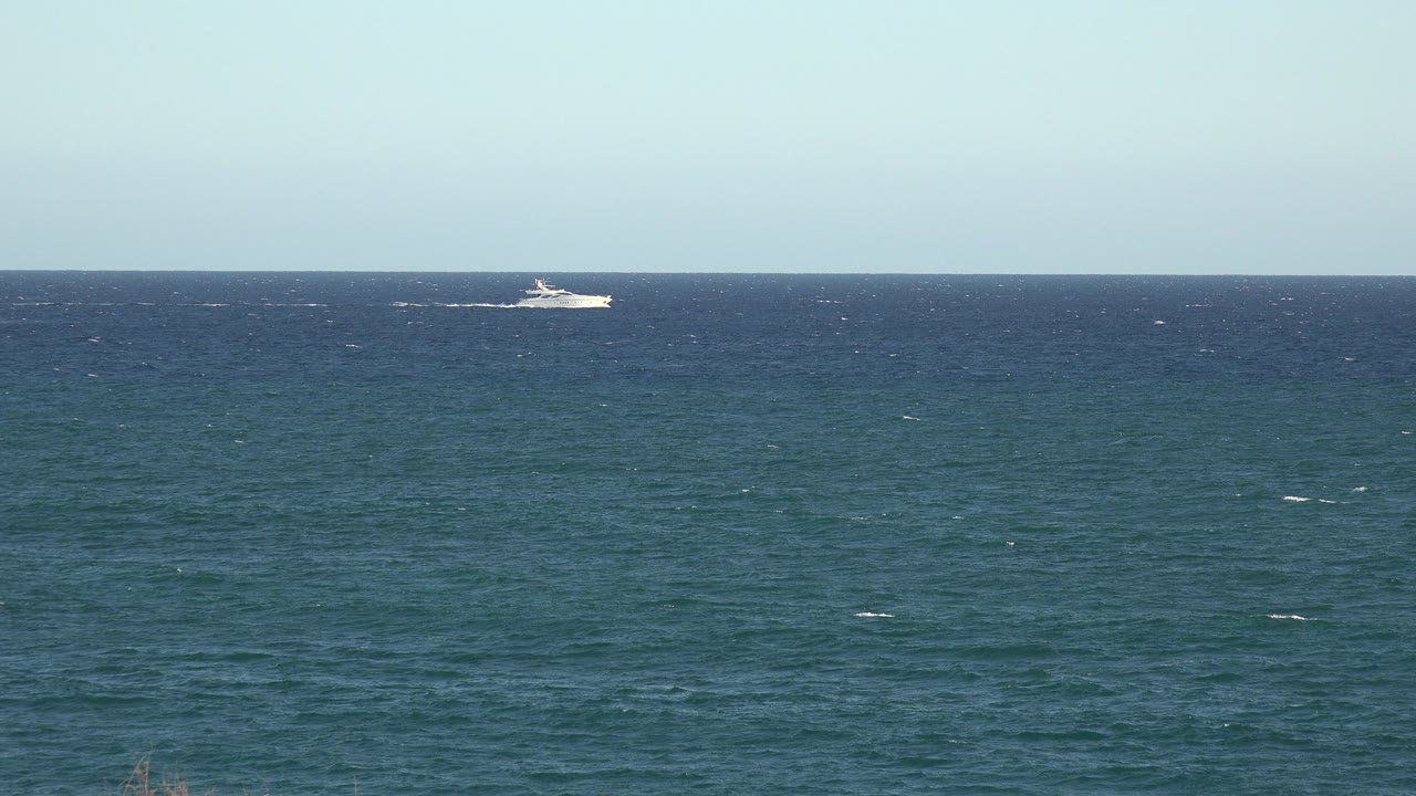 A distant white boat sits near the center of the ocean horizon in the Grand Junction, Colorado 2017 clip, with wind marks on the water and no visible people.