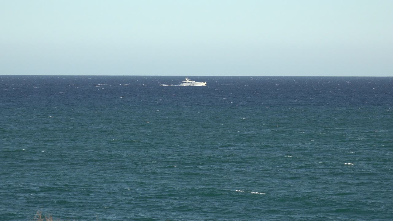 The white passenger ship remains near the far horizon in the Grand Junction, Colorado 2017 footage, with choppy blue water filling most of the frame and no visible people.