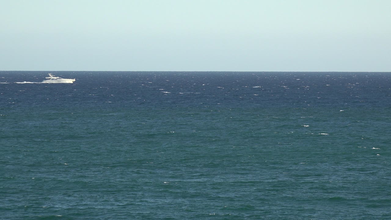 Opening frame from the Grand Junction Colorado 2017 clip showing a distant white passenger ship near the left horizon over blue ocean, with no visible people.