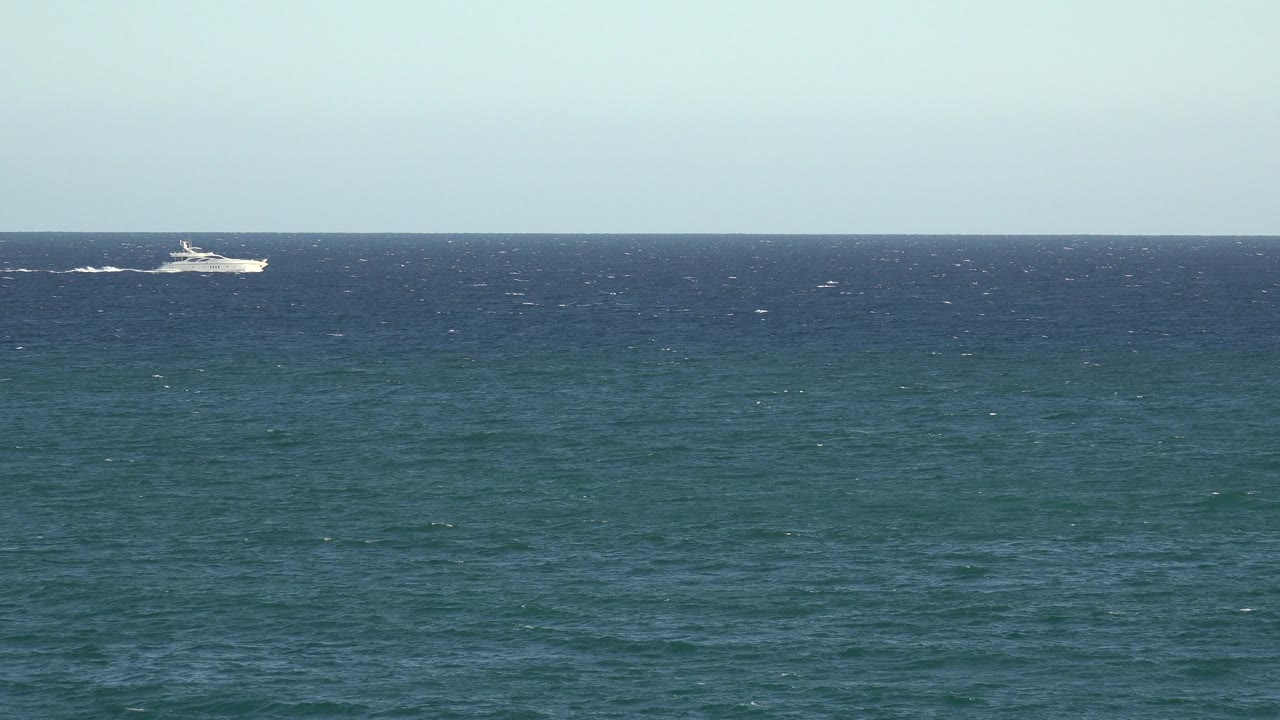 Small passenger ship crossing the distant ocean horizon.