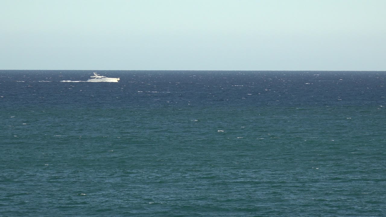 Small white ship near the horizon over choppy water