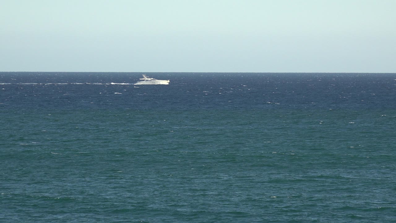 Wide ocean view with a small white boat near the horizon