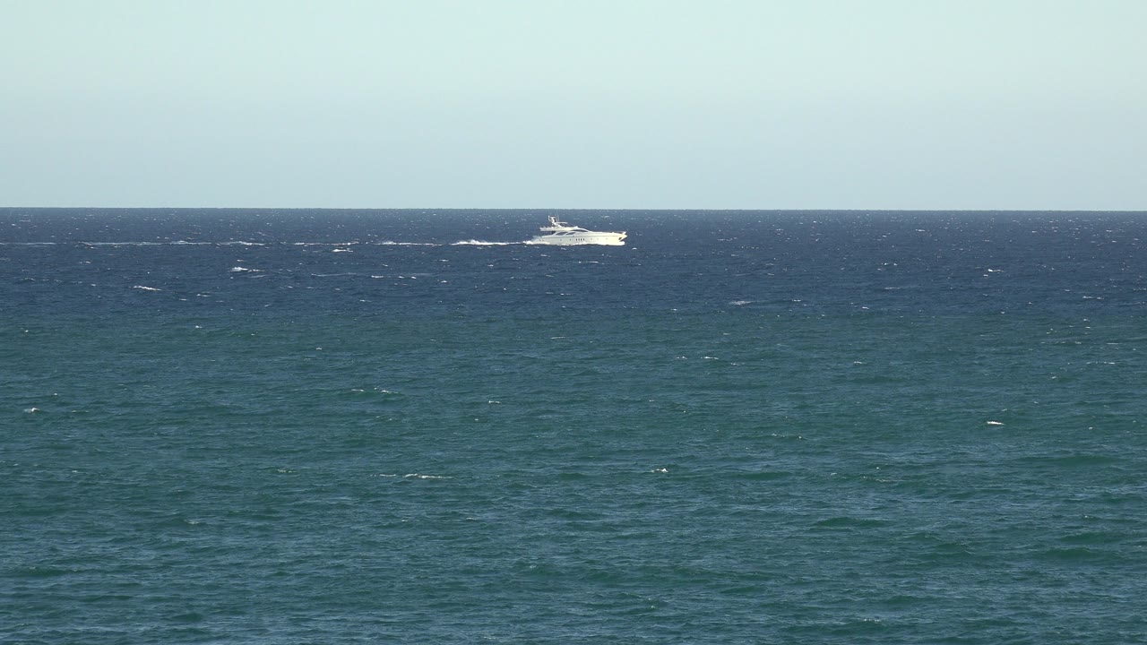 Distant white boat near the horizon over blue-green water.