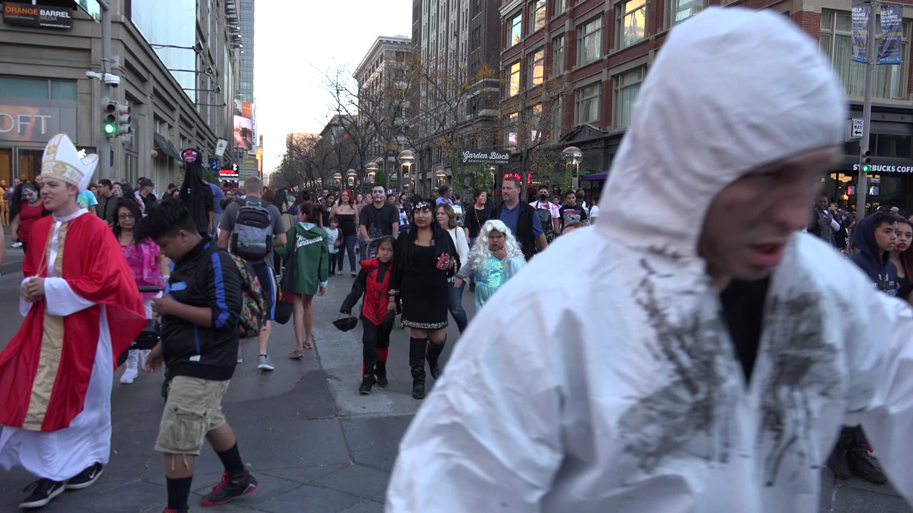 Busy city street crowd with a white hooded man close to the camera.