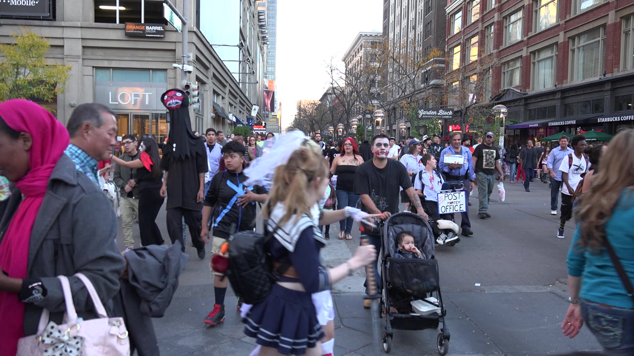 Costumed pedestrians and a stroller in a downtown crowd.