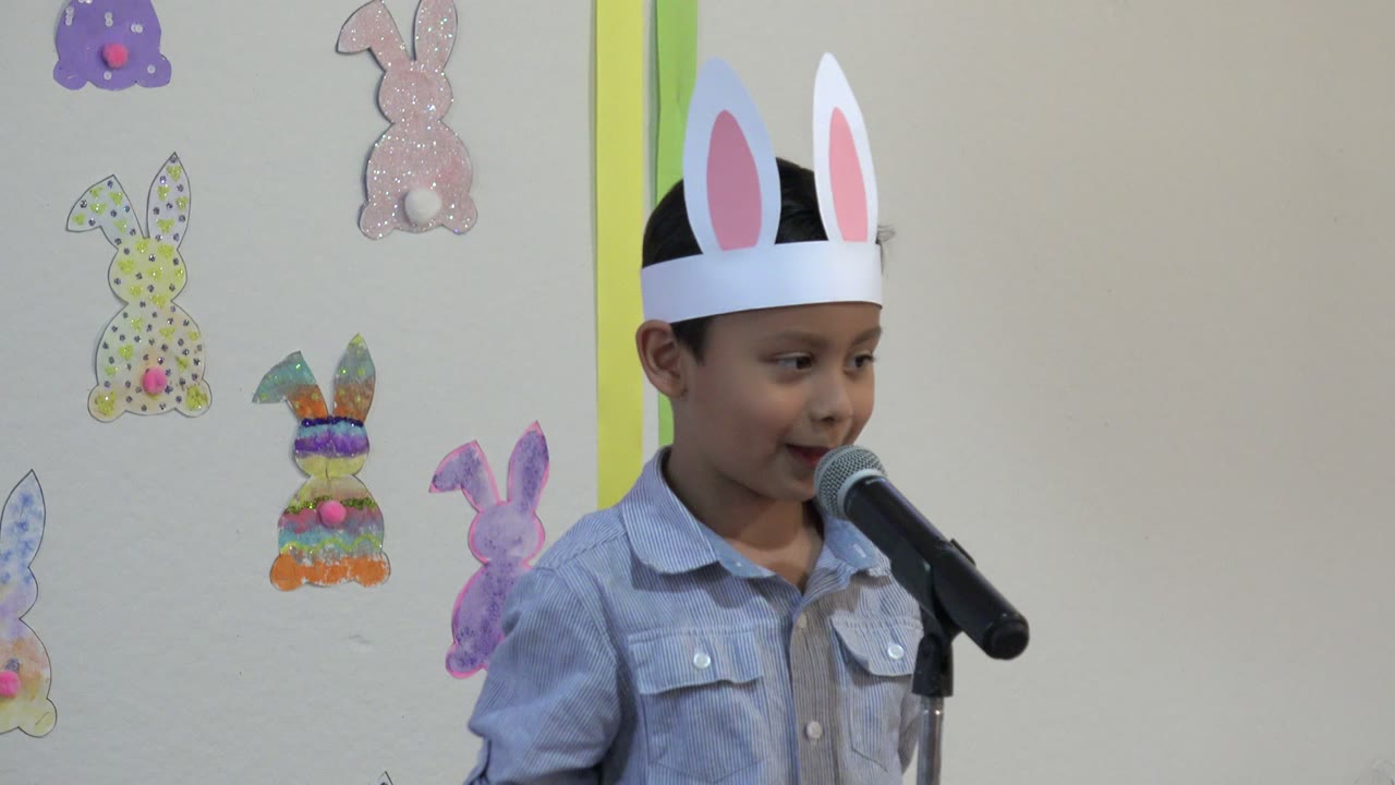 The boy in Cabo San Lucas, Mexico, turns slightly toward the microphone, with pink, yellow, purple, and multicolor bunny decorations visible on the wall behind him.