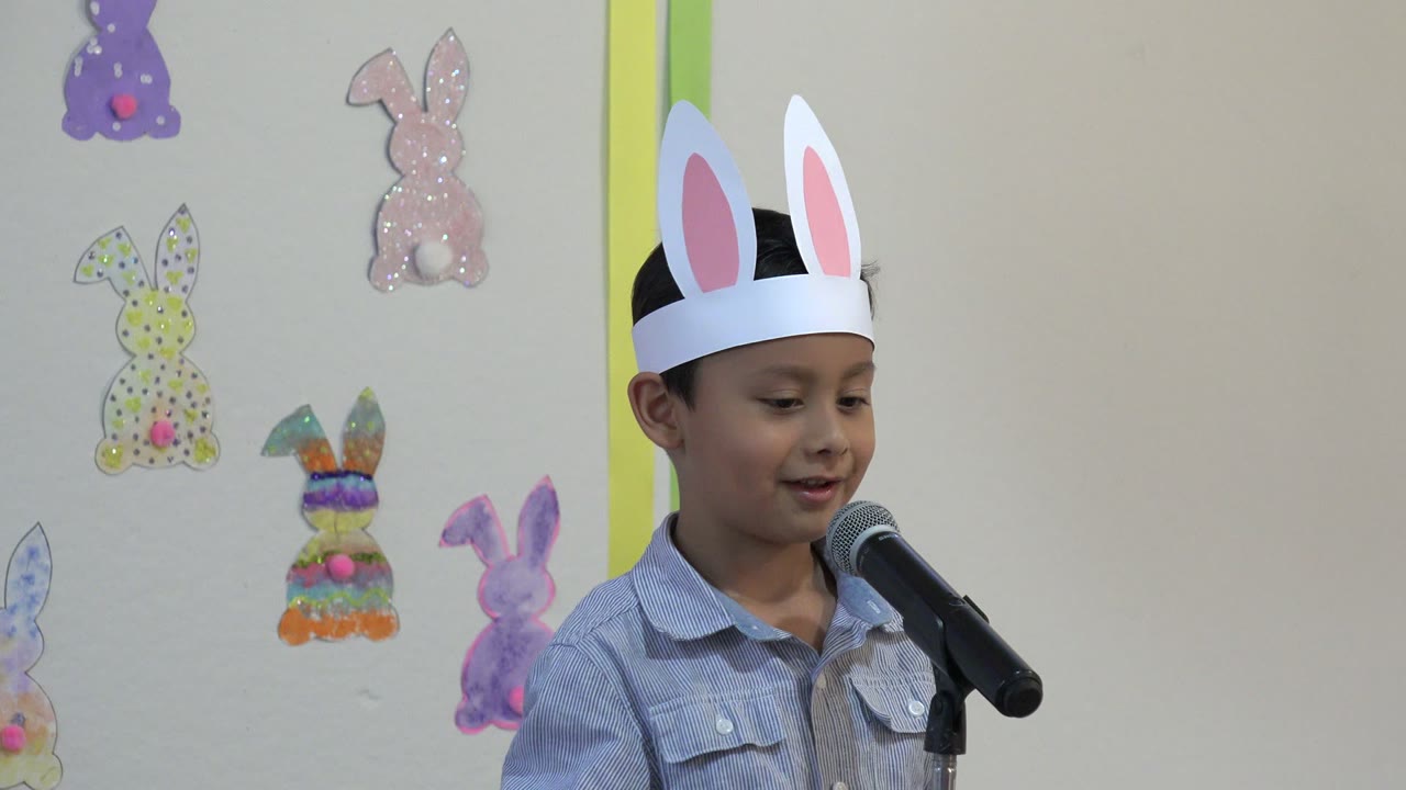 One second in, the child in Cabo San Lucas looks toward the microphone while wearing tall white rabbit ears, with pastel rabbit decorations visible on the wall.