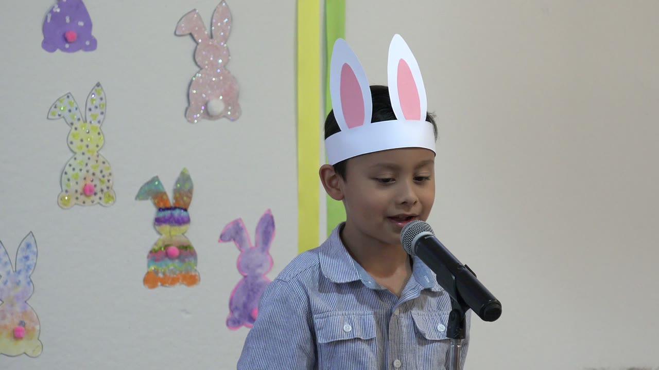 Child wearing bunny ears speaks into a microphone.