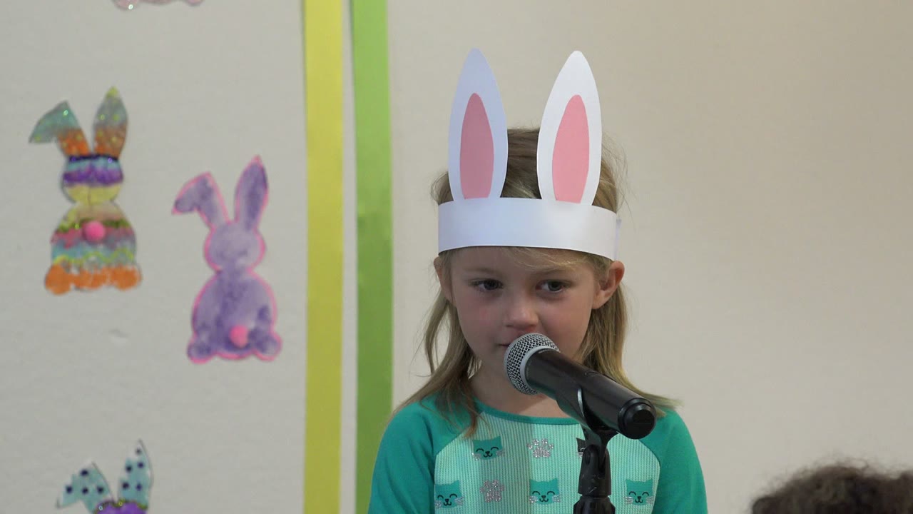 At 0:01 in Cabo San Lucas, Mexico, the girl faces more toward the microphone with colorful rabbit drawings visible on the wall behind her.