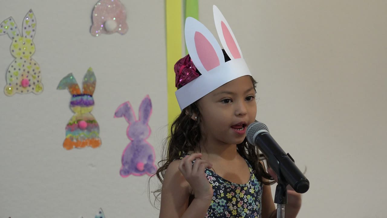 Young girl in bunny ears speaking into a microphone