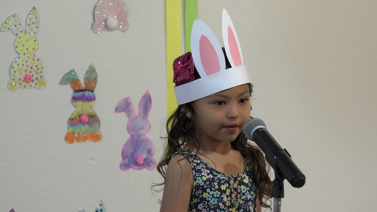 At 0:01 in Cabo San Lucas, Mexico, the girl looks toward the microphone, with her white bunny-ear headband high in frame and handmade bunny artwork behind her.